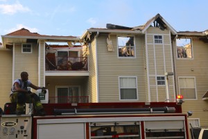 A firefighter sits on top of a Seminole County Fire Department fire truck and views the burned apartment building, which was claimed a total loss. Photo by Katrina Poggio.