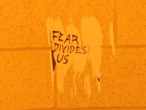 UCF College Democrats officer Peter Yañez wrote 'Fear Divides Us.' messages over the white patches left behind by removed white nationalist fliers. Photo by: Cristóbal Reyes